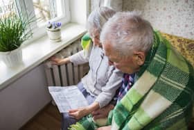 File photo of elderly couple in front of a heating radiator, holding an energy bill. Picture: Solarisys - stock.adobe.com