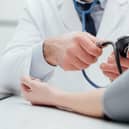 Doctor checking blood pressure of a patient, he is measuring pulses with a sphygmomanometer, hands close up