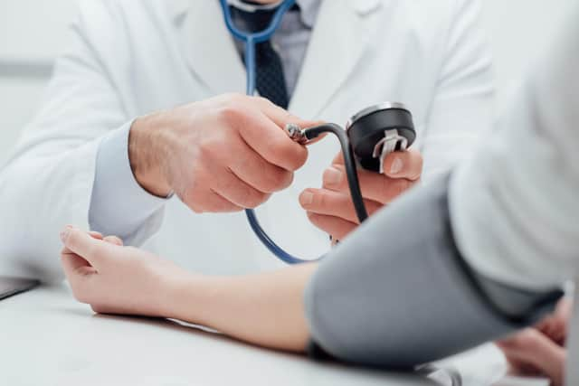 Doctor checking blood pressure of a patient, he is measuring pulses with a sphygmomanometer, hands close up