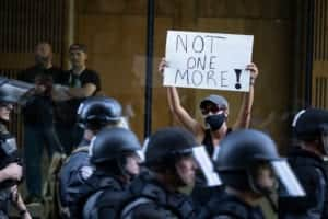 A protester holds a sign as police in riot gear move down the street in formation in Louisville, Kentucky (Photo: Brett Carlsen/Getty Images)