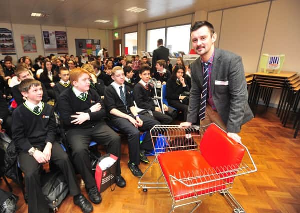 Dragon's Den star Max McMurdo with one of his chairs talking to school students